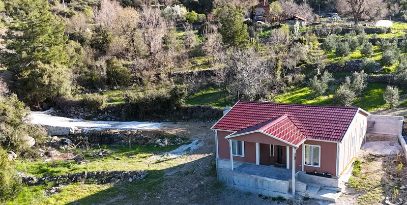 Zeytin terasları ve çamlı tepeler arasındaki evin geniş açılı havadan görünümü