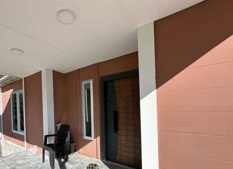 Mermer görünümlü seramikli kapalı veranda, ahşap kaplamalı giriş kapısı ve dar yan pencere